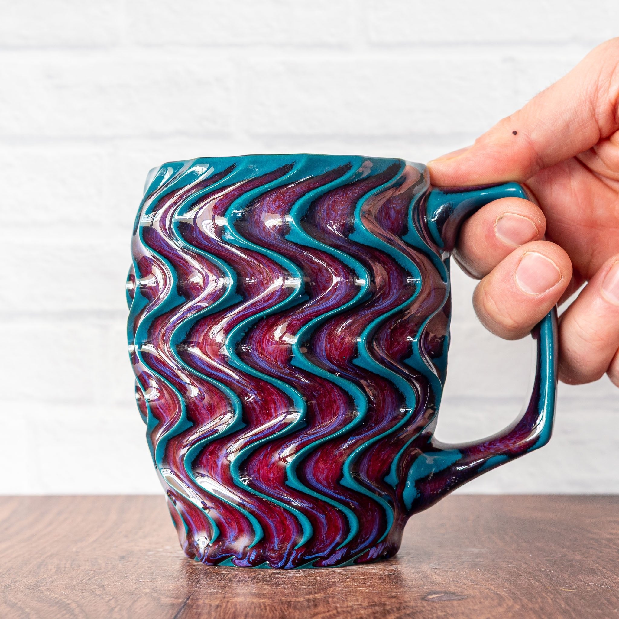 Hammerly Ceramics handmade slip-cast mug in glossy deep crimson and teal, deep wavy textured porcelain with angular handle