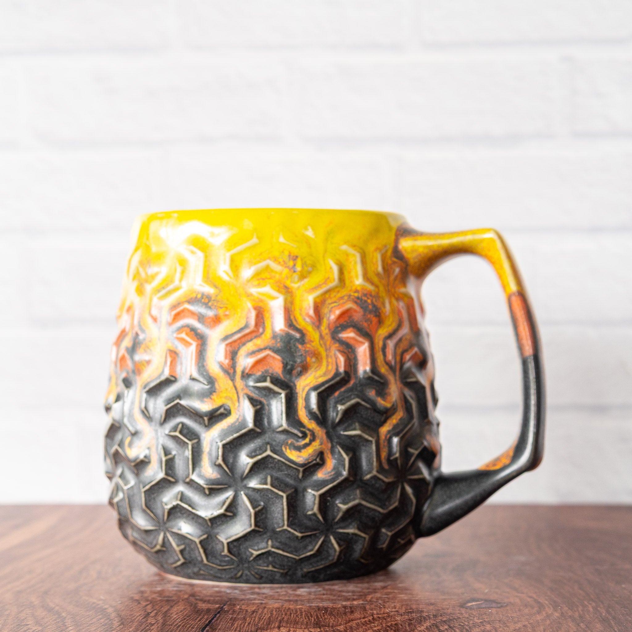 Hammerly Ceramics handmade slip-cast mug in cascading orange and yellow over matte black, interlocking geometric weave textured porcelain