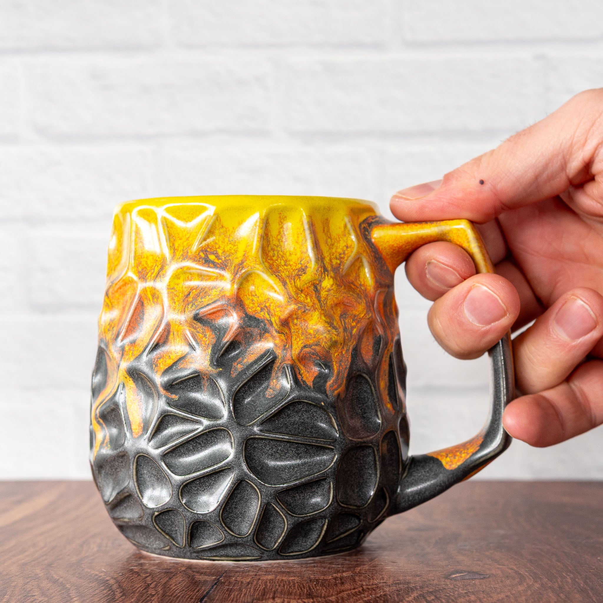 Hammerly Ceramics handmade slip-cast mug in cascading orange and yellow over matte black, geometric organic cell-like textured porcelain