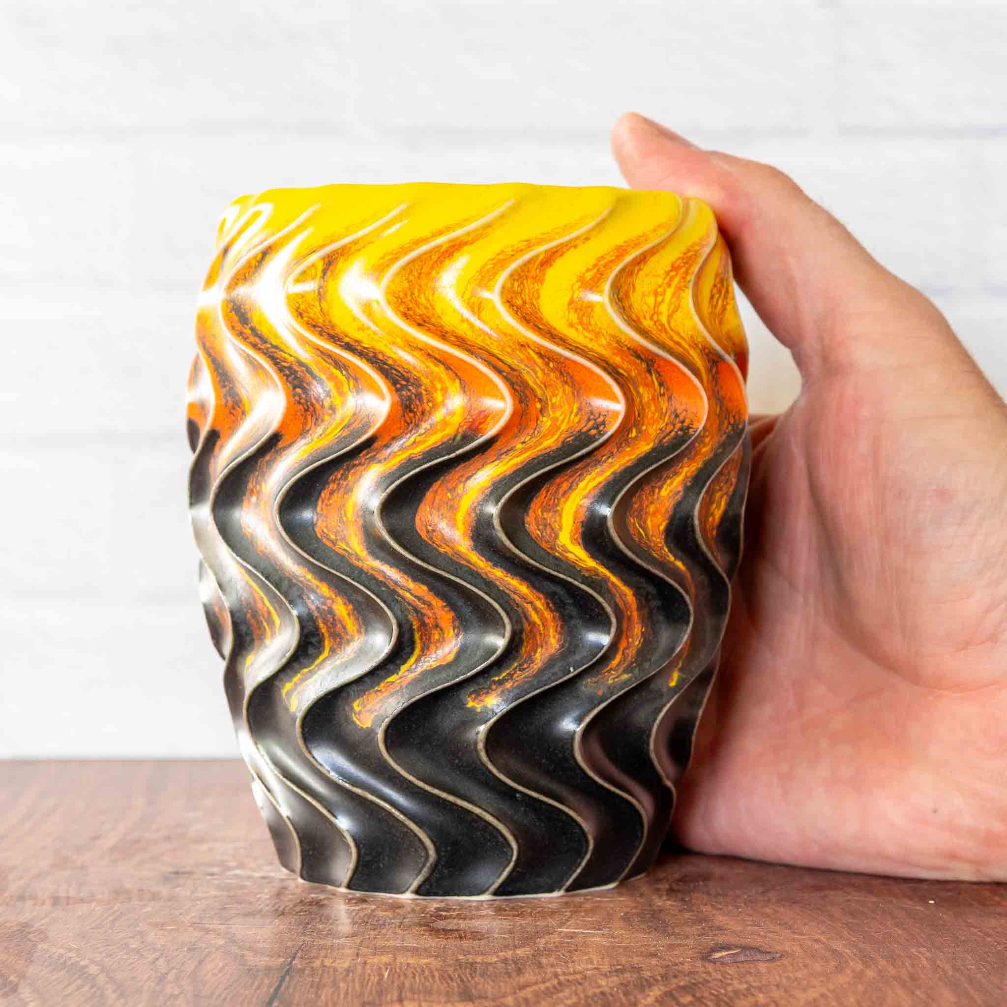 Hammerly Ceramics handmade slip-cast cup in cascading orange and yellow over matte black, deep wavy textured porcelain