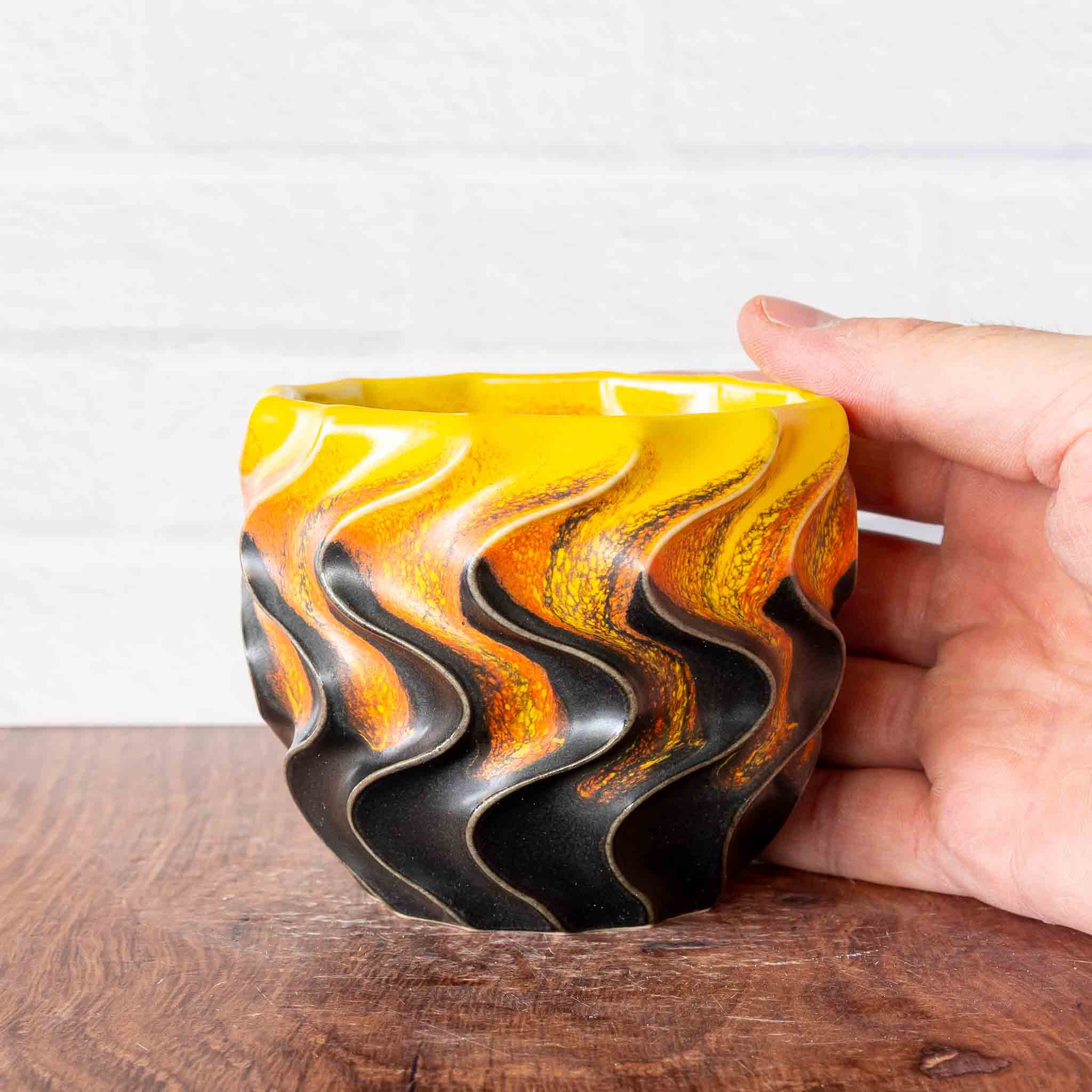 Hammerly Ceramics handmade slip-cast cup in cascading orange and yellow over matte black, deep wavy textured porcelain