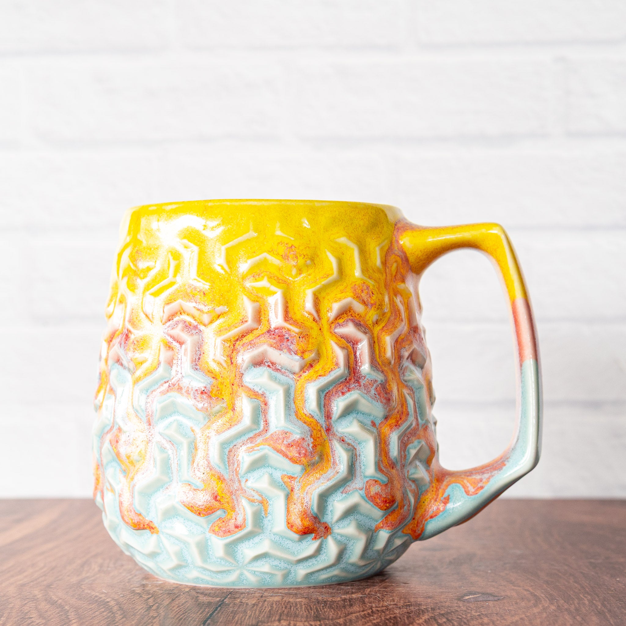 Hammerly Ceramics handmade slip-cast mug in yellow and sky blue with flowing orange blush, interlocking geometric weave textured porcelain