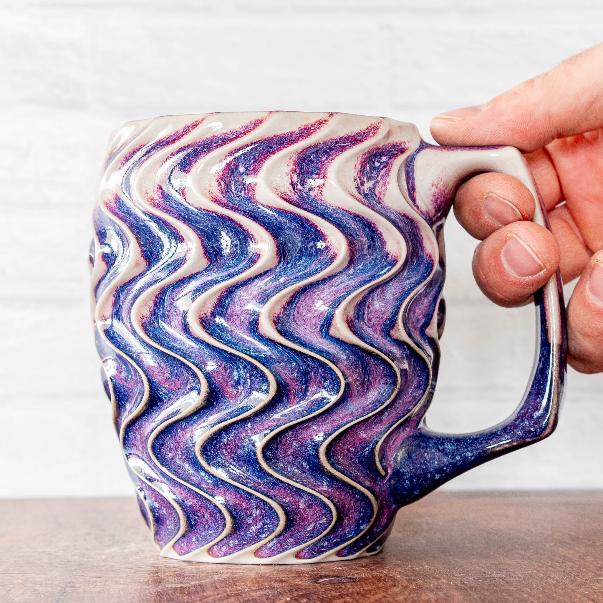 Hammerly Ceramics handmade slip-cast mug in white and deep navy glaze with purple drip transition, deep wavy textured porcelain with angular handle