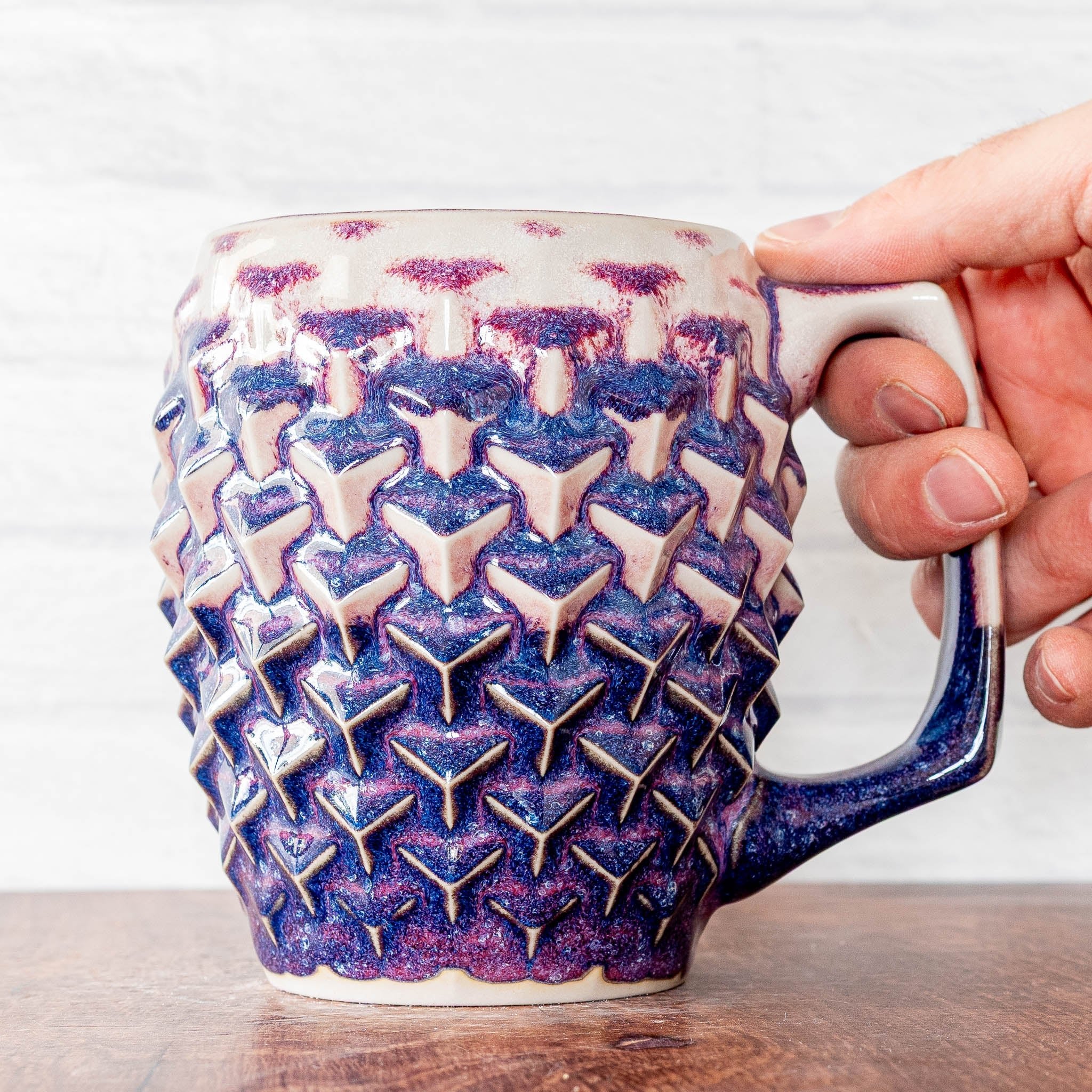 Hammerly Ceramics handmade slip-cast mug in white and deep navy glaze with purple drip transition, geometric cubes textured porcelain