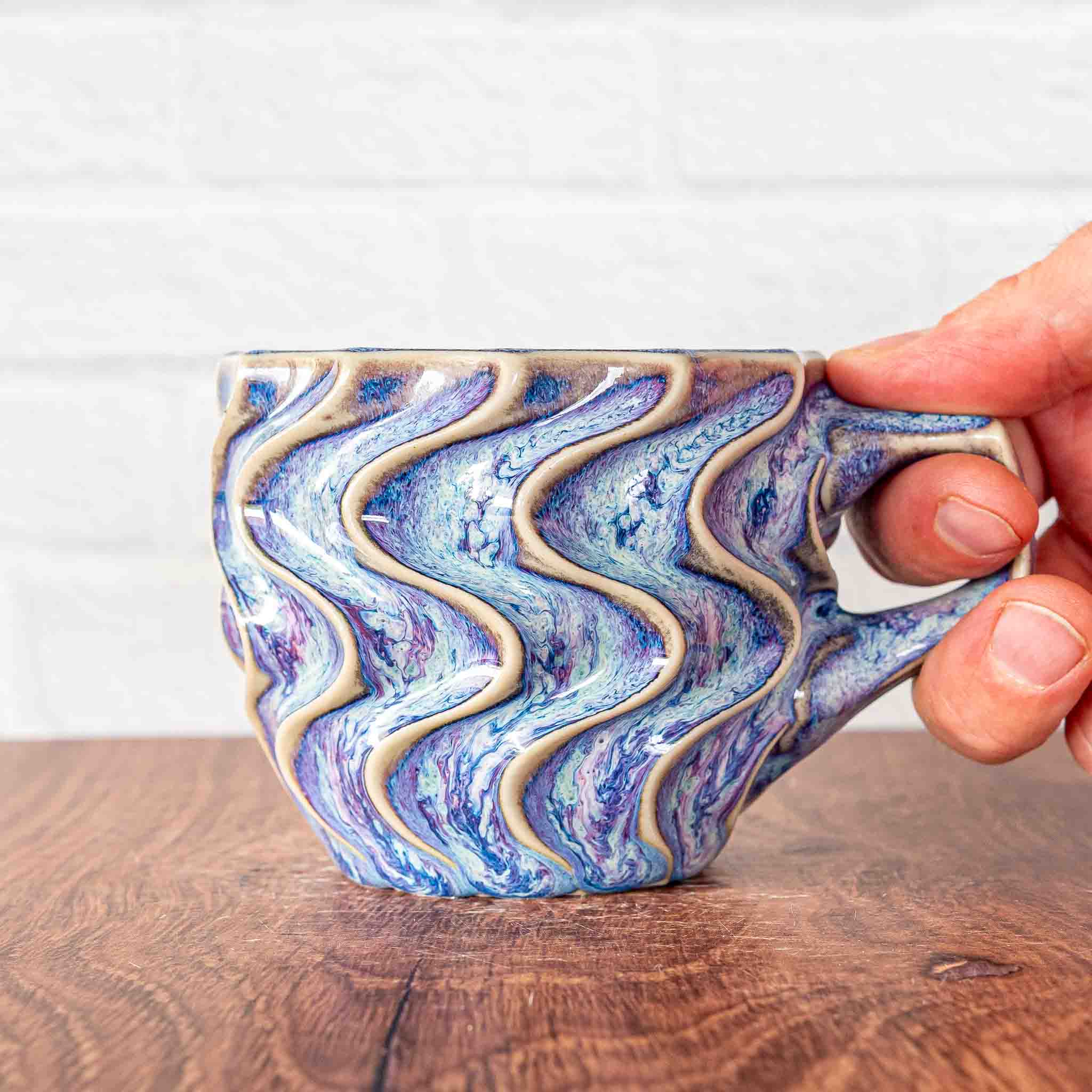 Hammerly Ceramics handmade slip-cast mug in swirls of various shades of blue, deep wavy textured porcelain with angular handle
