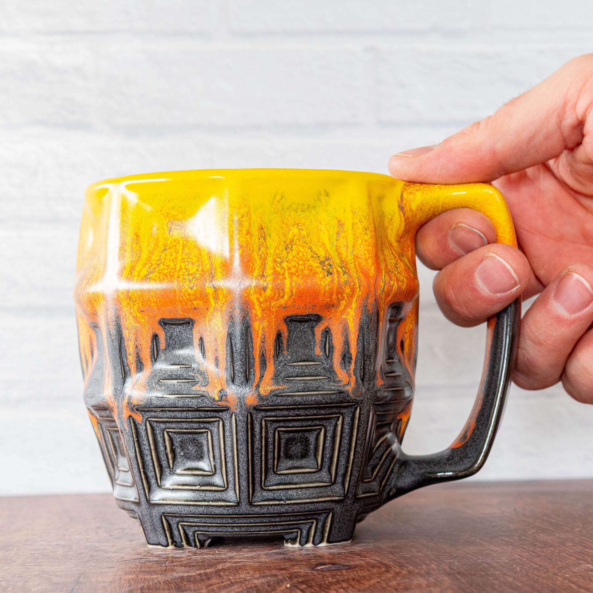 Hammerly Ceramics handmade slip-cast mug in cascading orange and yellow over matte black, barrel-shaped with concentric recessed squares 