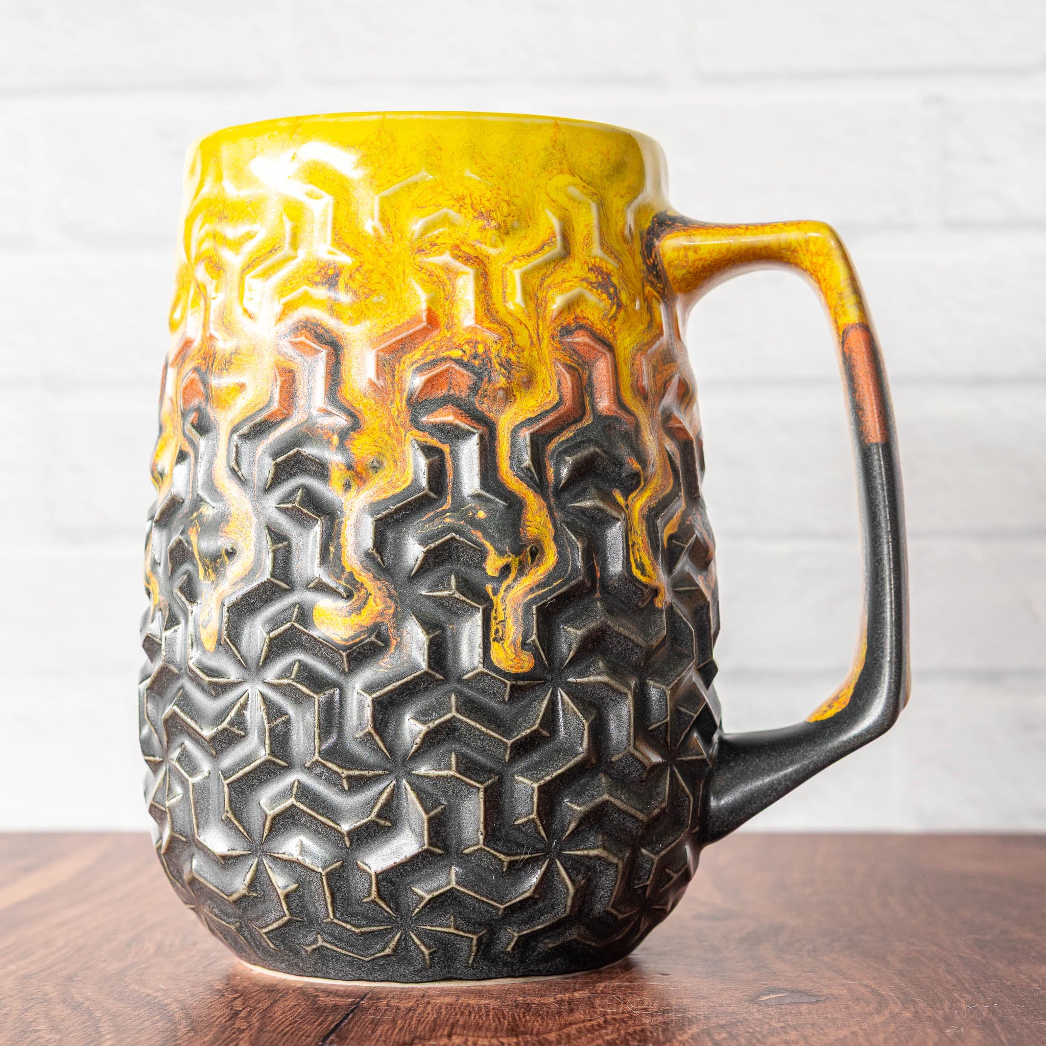Hammerly Ceramics handmade slip-cast mug in cascading orange and yellow over matte black, interlocking geometric weave textured porcelain
