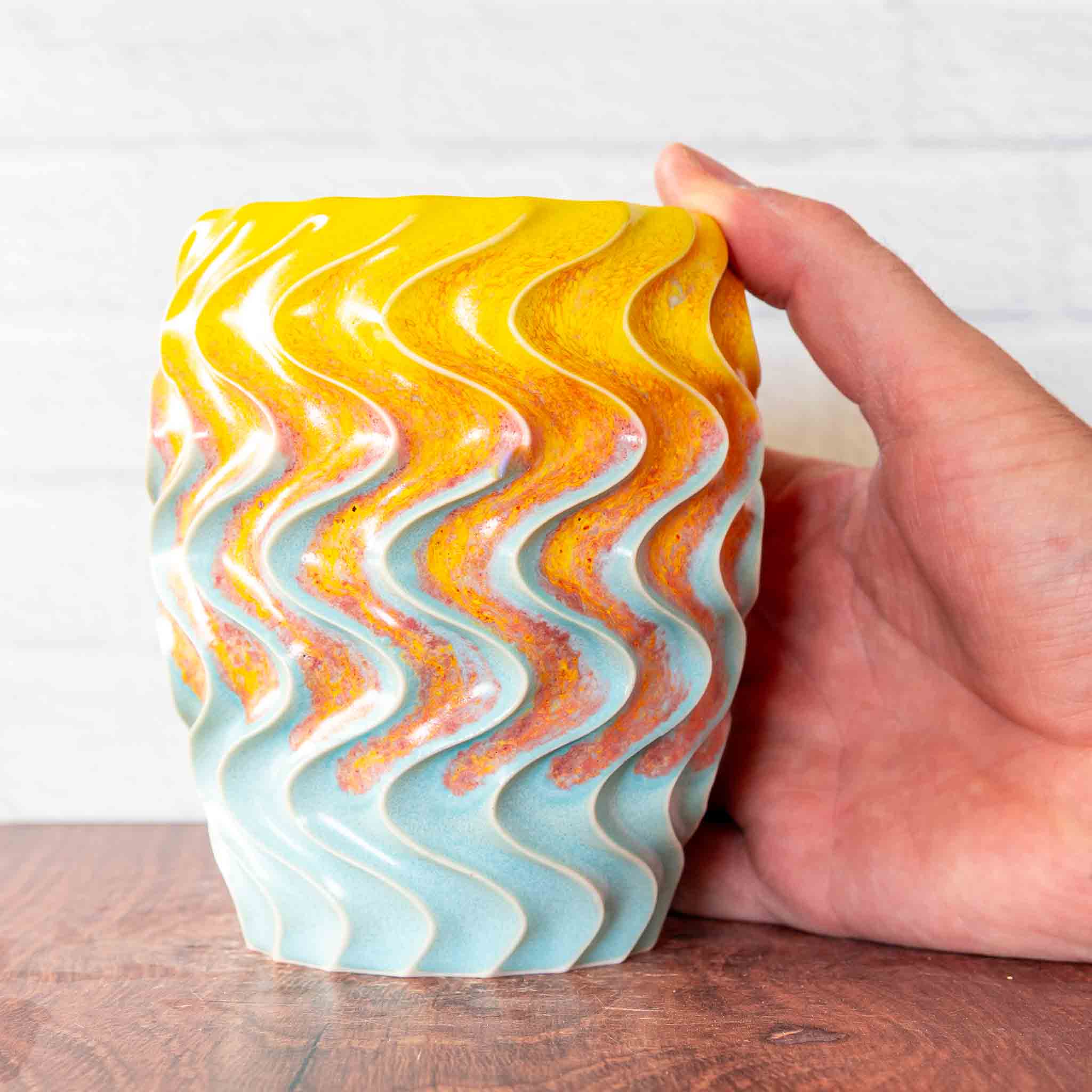 Hammerly Ceramics handmade slip-cast cup in yellow and sky blue with flowing orange blush, deep wavy textured porcelain 