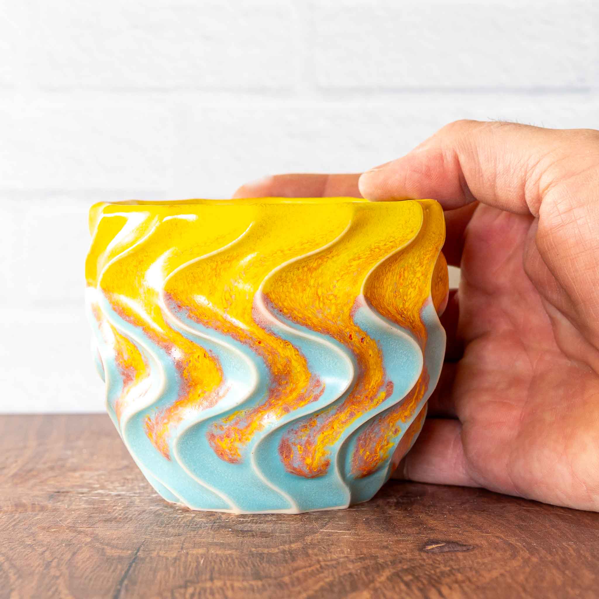 Hammerly Ceramics handmade slip-cast cup in yellow and sky blue with flowing orange blush, deep wavy textured porcelain 