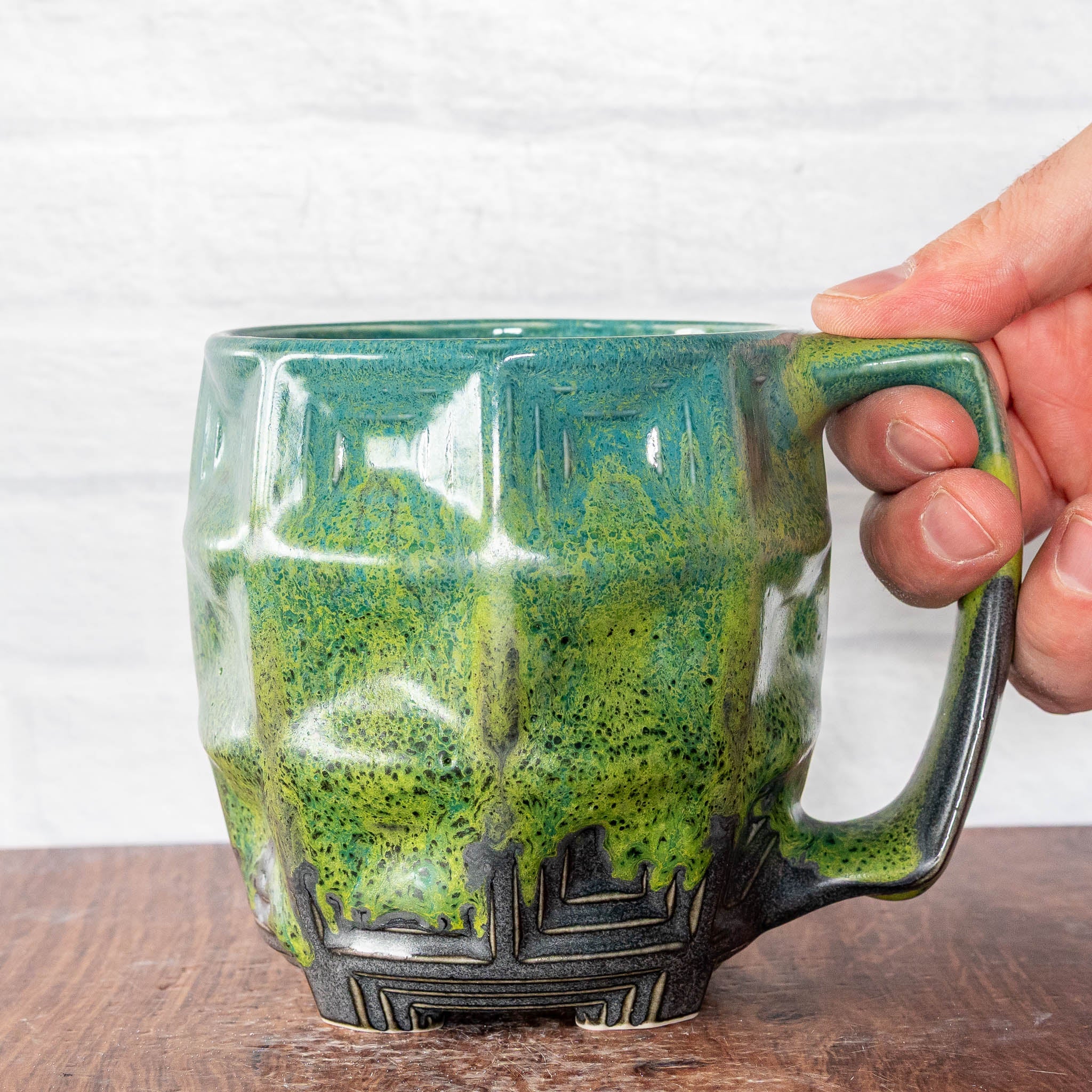 Hammerly Ceramics handmade slip-cast mug in light green and teal flowing over charcol black, barrel-shaped with concentric recessed squares 