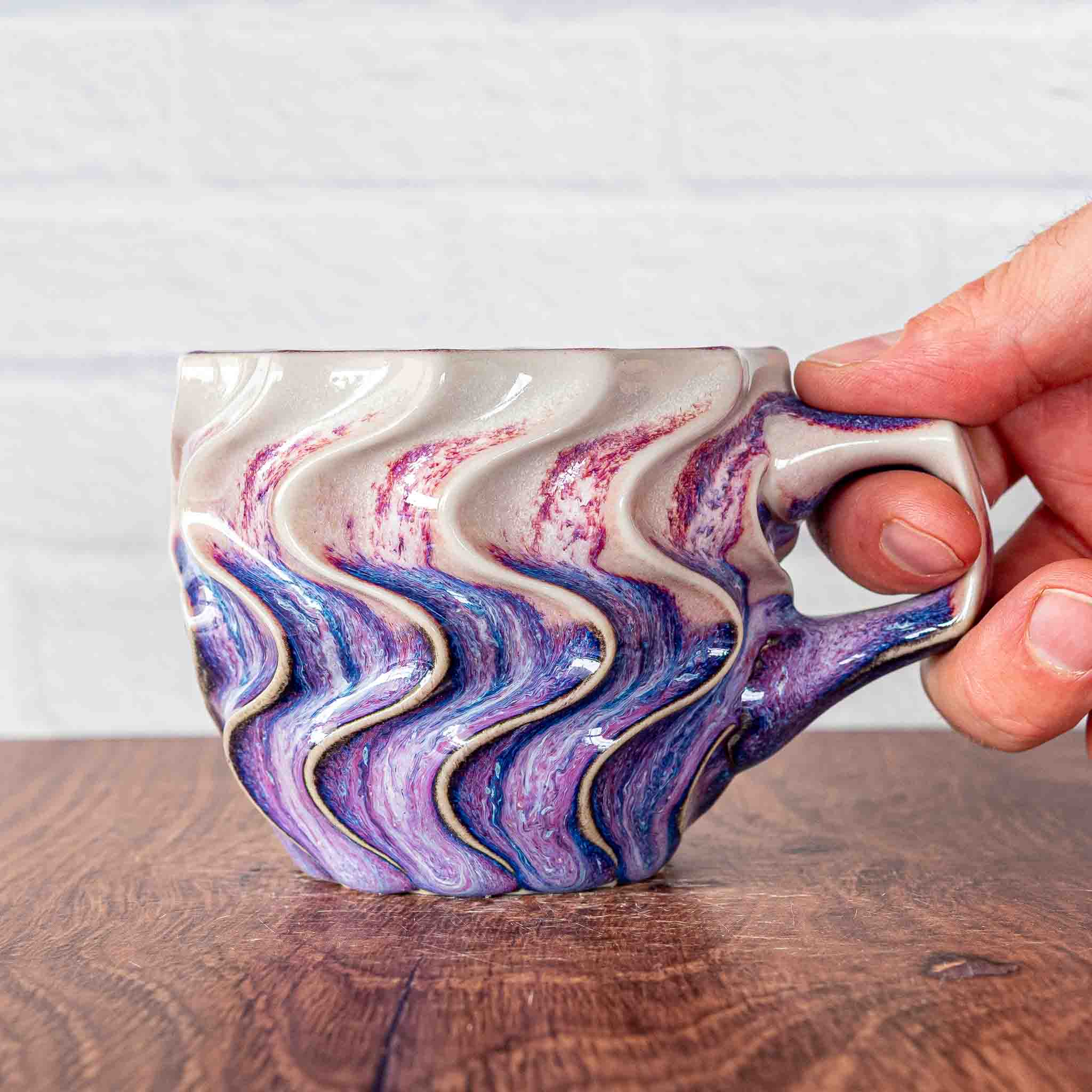 Hammerly Ceramics handmade slip-cast mug in white and deep navy glaze with purple drip transition, deep wavy textured porcelain with angular handle
