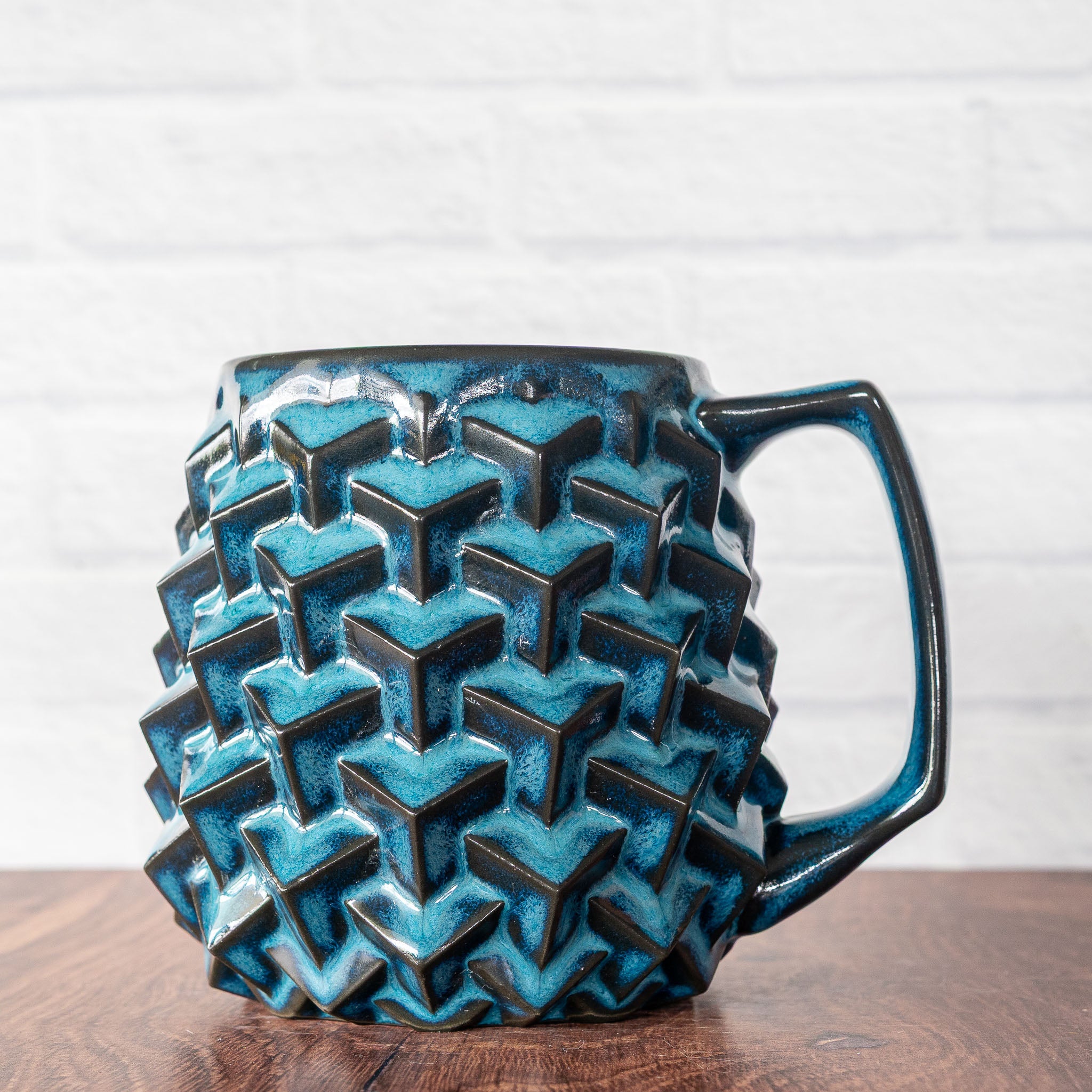 Hammerly Ceramics handmade slip-cast mug in ocean blue glaze with dark charcoal edges, geometric cubes textured porcelain