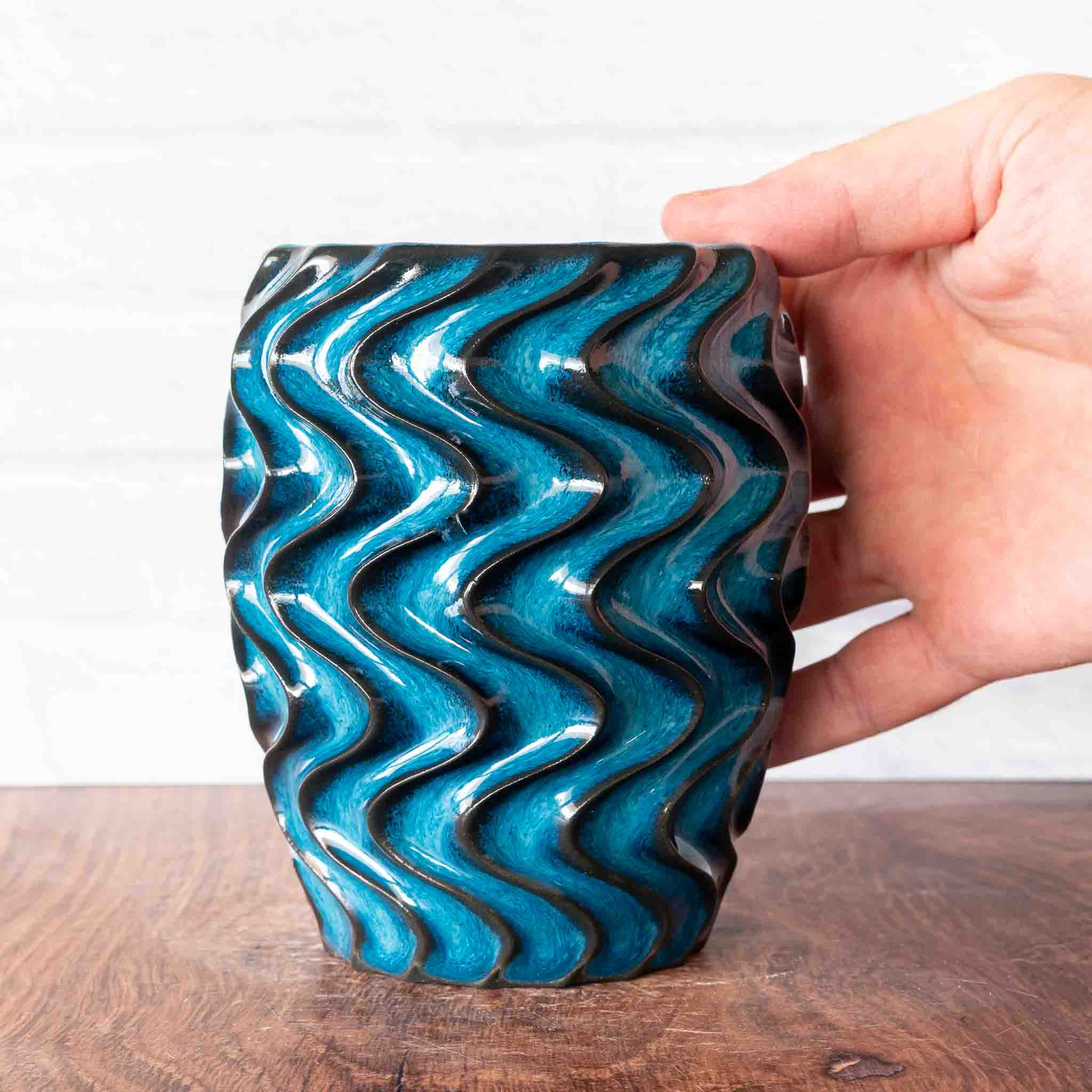 Hammerly Ceramics handmade slip-cast cup in ocean blue glaze with dark charcoal edges, deep wavy textured porcelain 