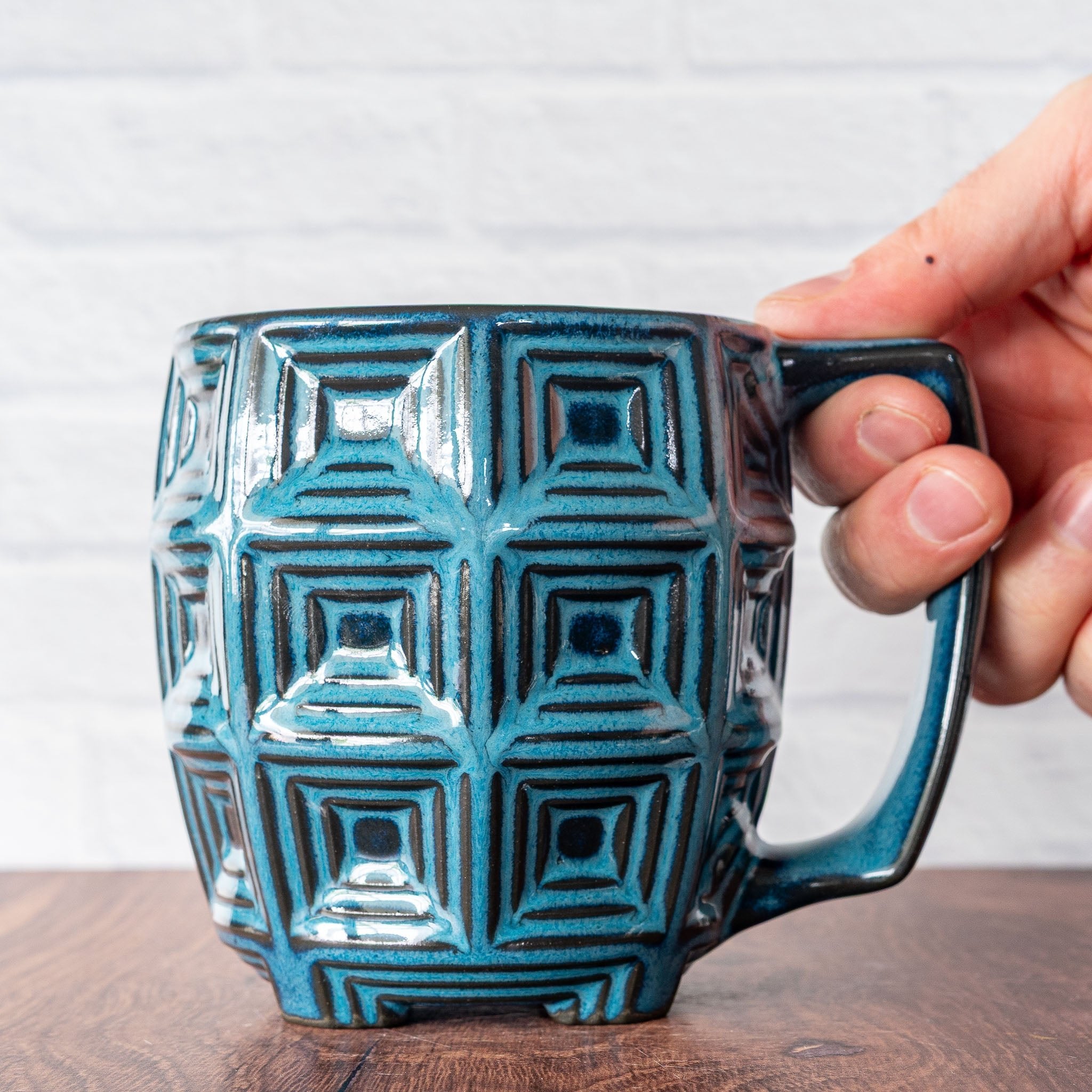 Hammerly Ceramics handmade slip-cast mug in ocean blue glaze with dark charcoal edges, barrel-shaped with concentric recessed squares 