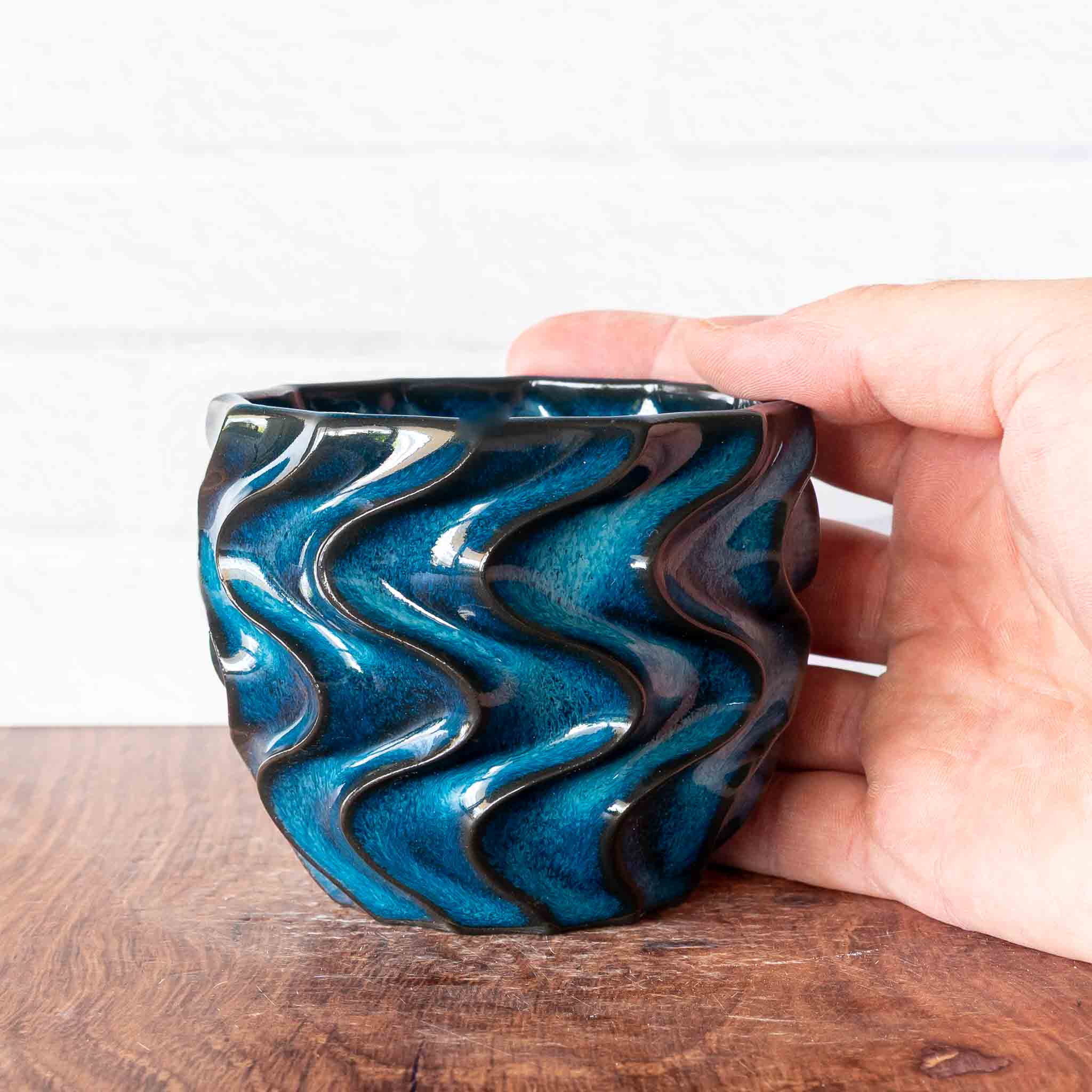 Hammerly Ceramics handmade slip-cast cup in ocean blue glaze with dark charcoal edges, deep wavy textured porcelain 