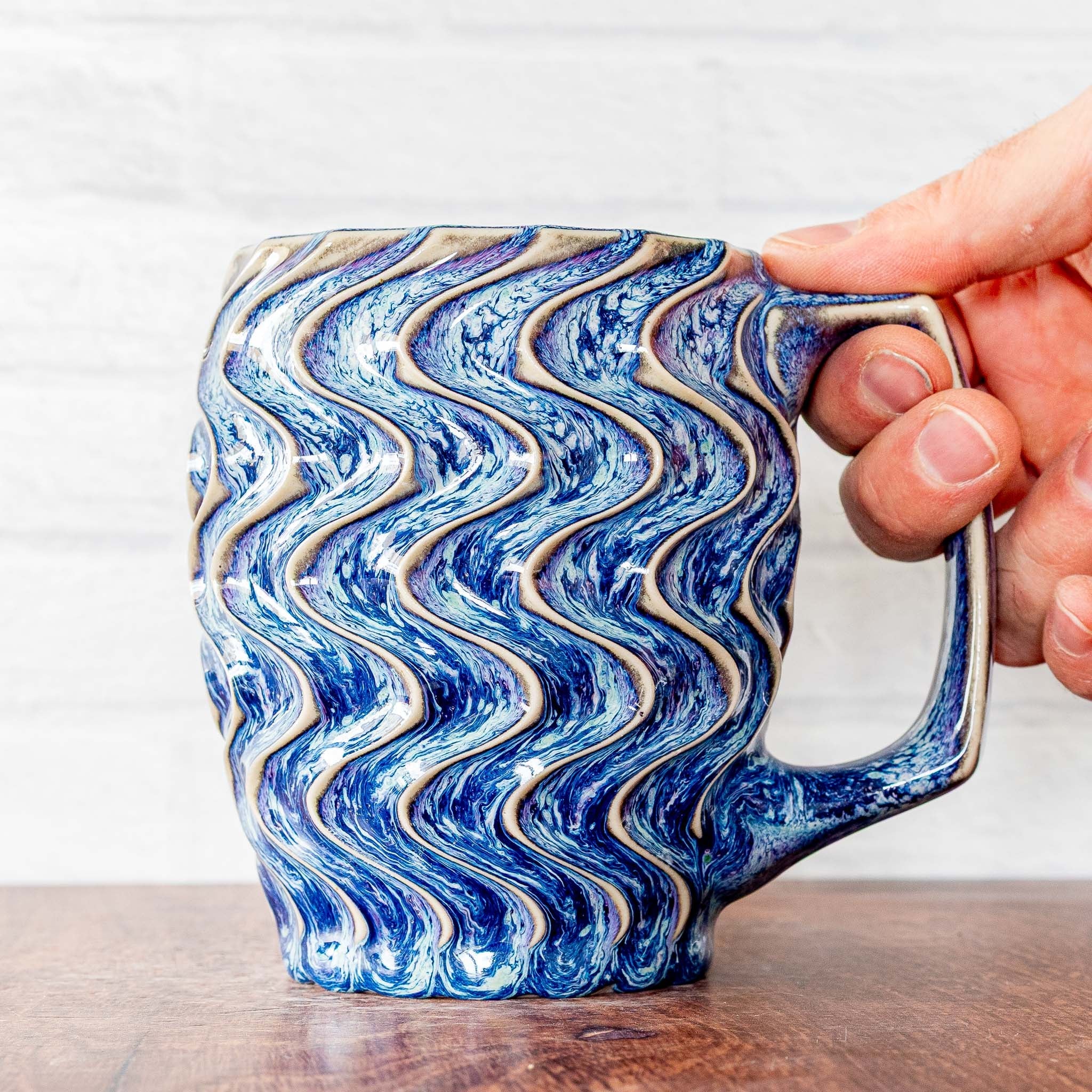 Hammerly Ceramics handmade slip-cast mug in swirls of various shades of blue, deep wavy textured porcelain with angular handle
